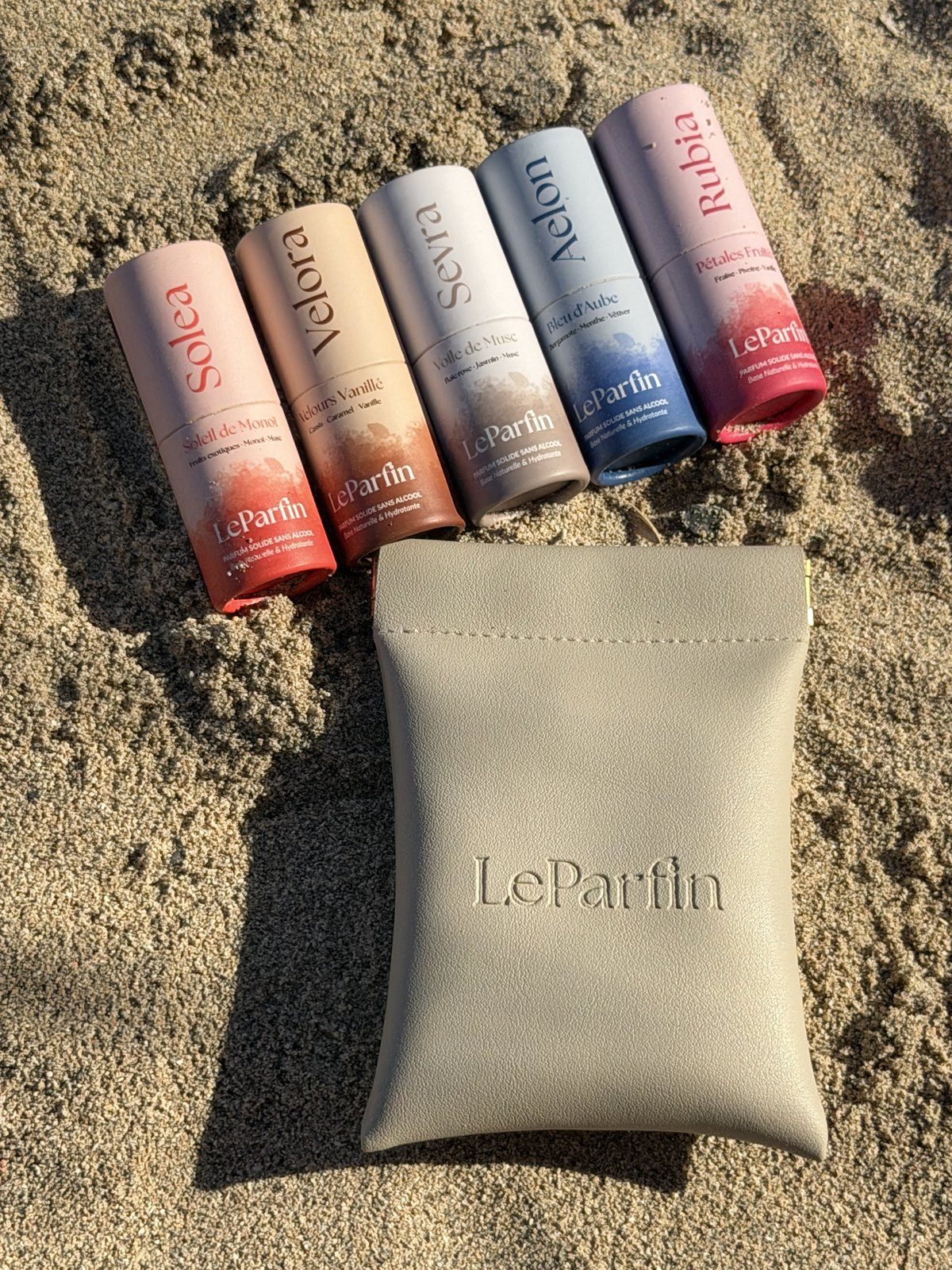 El neceser LeParfin y cinco perfumes sólidos sobre la arena